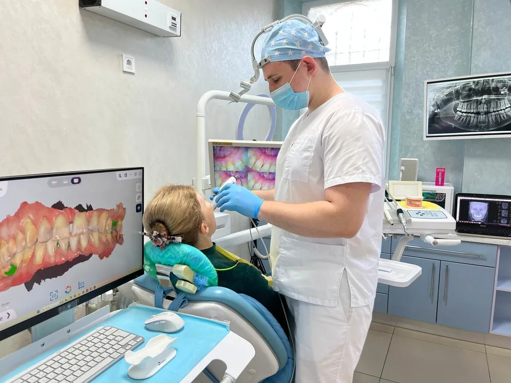 Лікар із дитиною-пацієнтом біля комп’ютера з 3D-сканом зубів